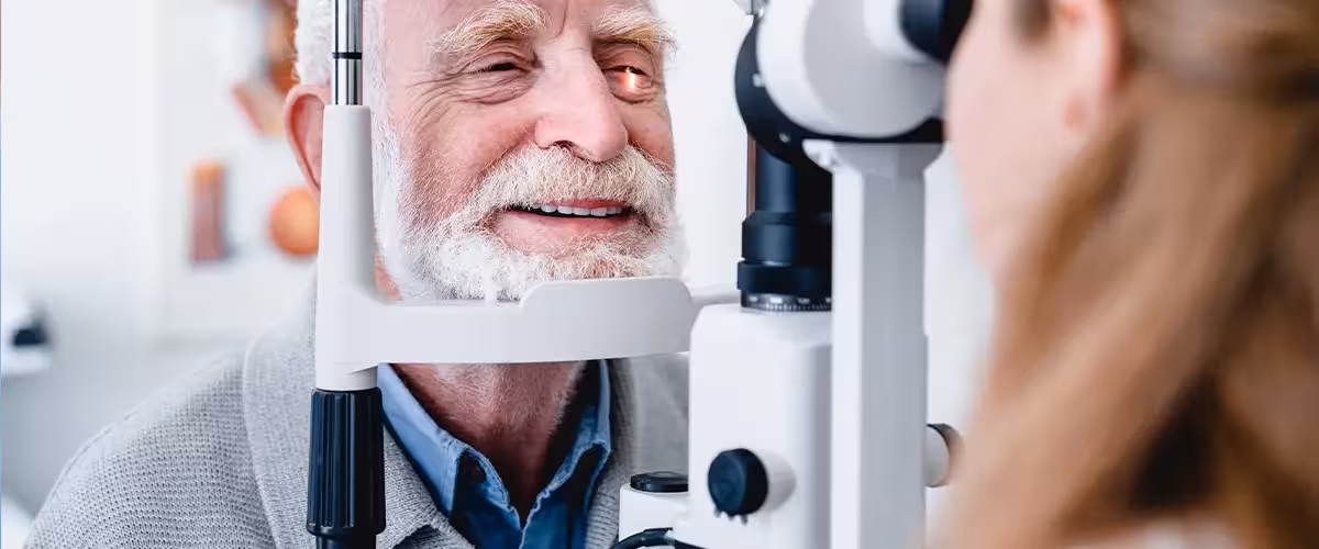 Smiling cheerful elderly patient being checked on eye by female ophthalmic doctor. Cost of private cataract surgery UK.