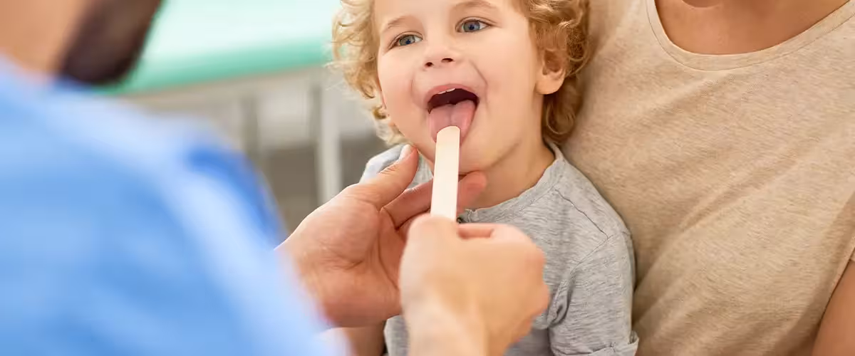 Pediatrician Examining Childs throat. Cost of private tonsillectomy surgery in UK.