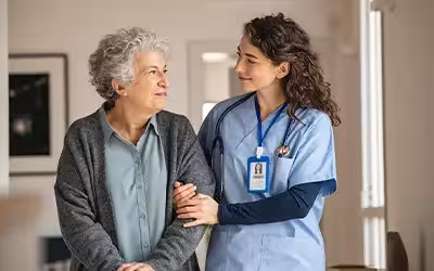 Caregiver assist senior woman at home. Cost of private colonoscopy UK.