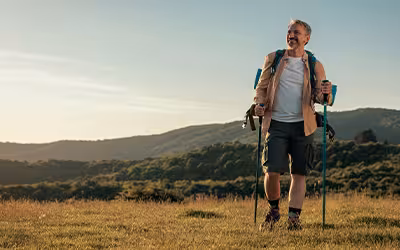 Smiling middle-aged man hiking on a mountain trail.