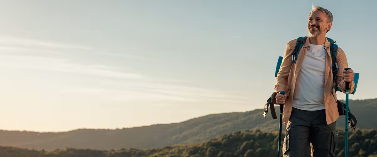 Smiling middle-aged man hiking on a mountain trail.
