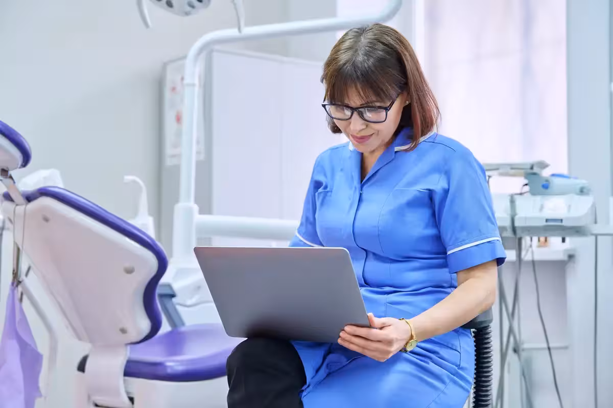 Female dentist in the UK looking at paperwork. Difference Between Private Dentists and NHS Dentists