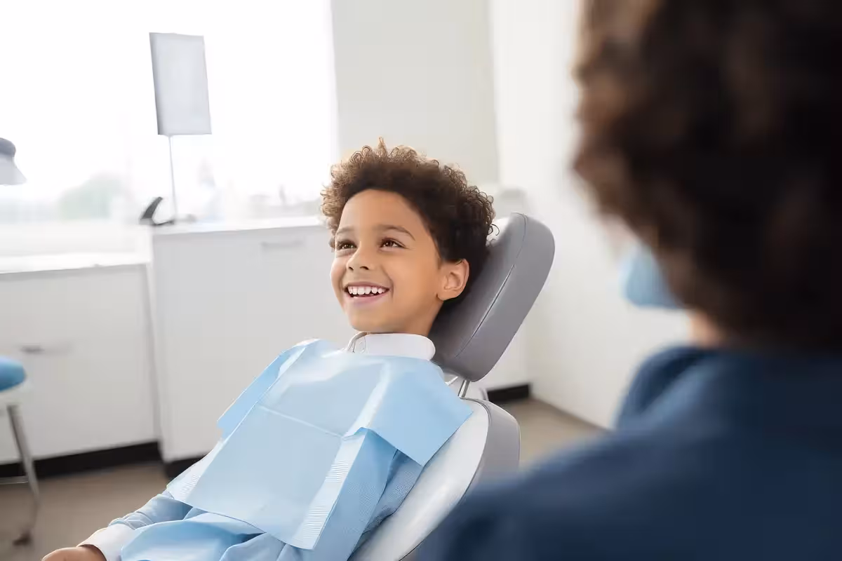 Child sat in dentist chair smiling. How To Find A Dentist In UK