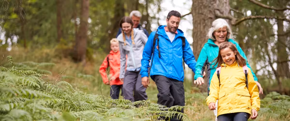 Family of 3 generations walking through woods wearing colourful waterproofs. Top Tips for Buying Life Insurance: Get Free Expert Advice.