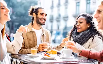 Friends chatting and laughing outside a cafe. Life Insurance For Smokers - Is It More Expensive?