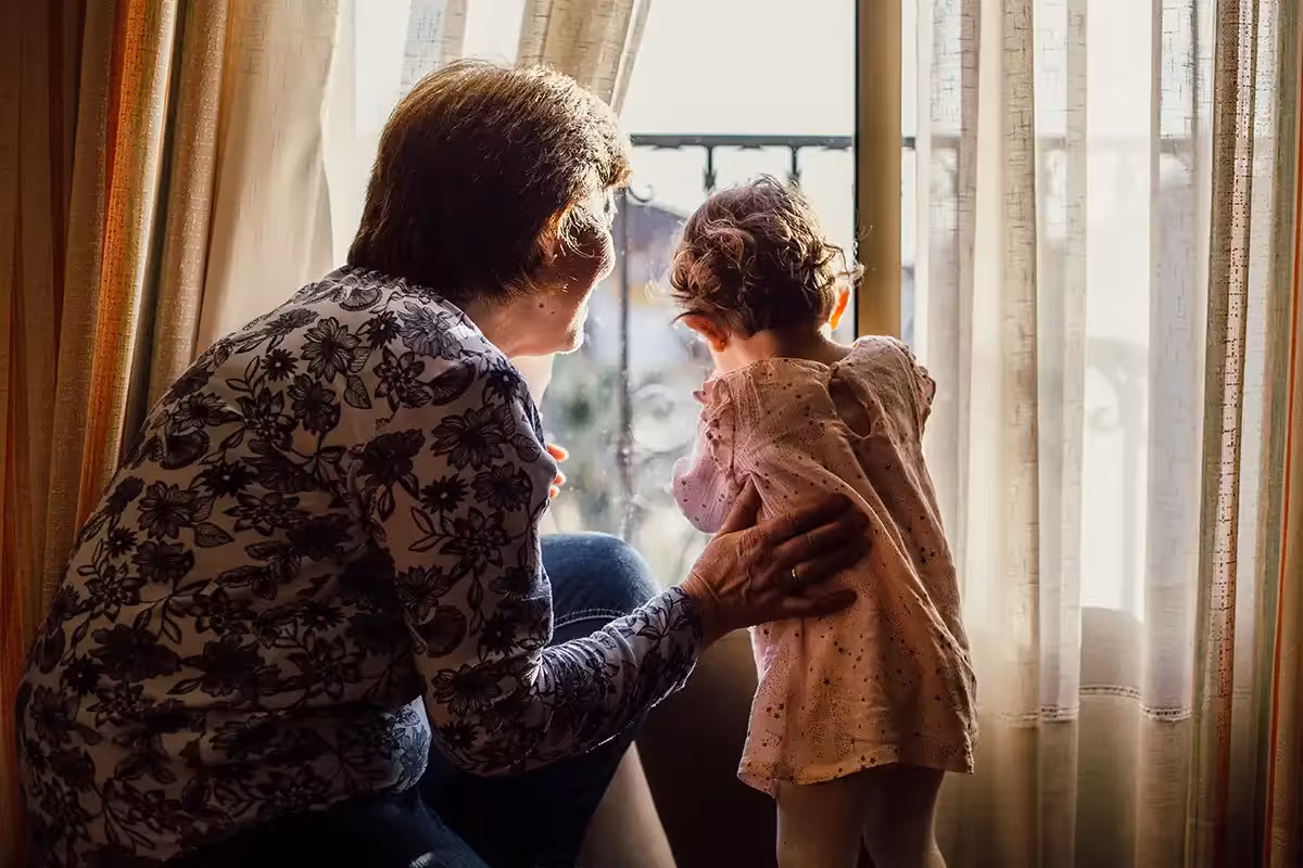 Grandmother and baby girl looking through a window together