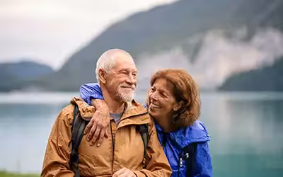 Senior pensioner couple hiking by lake in nature, resting. How Does Life Insurance Work In The UK?