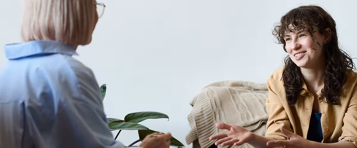 Young smiling woman talking to therapist while she making notes in document. Psychiatrist vs Psychologist.
