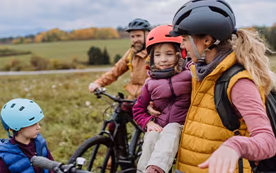 Young family with small children enjoying a bike adventure in nature. Everyone is wearing helmets, symbolising safety and protection, much like private health insurance.