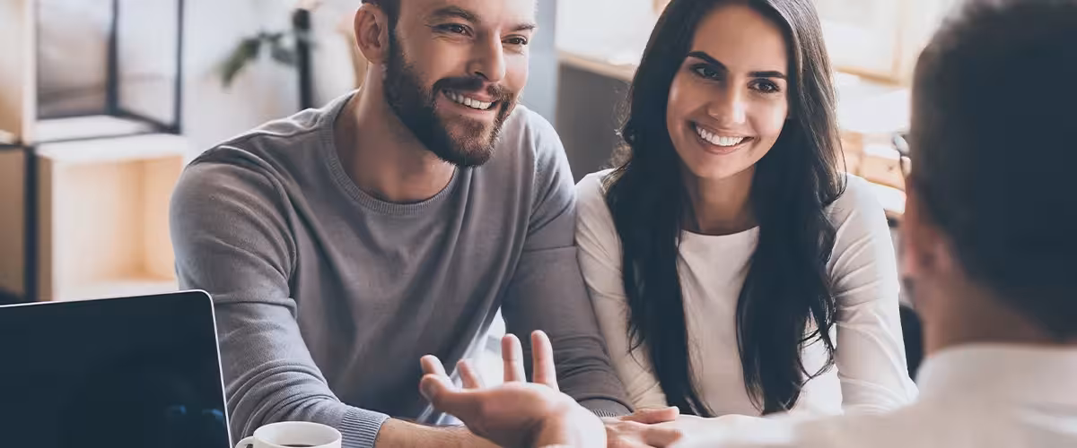 Happy couple getting advice about health insurance in the UK from an experienced broker. 