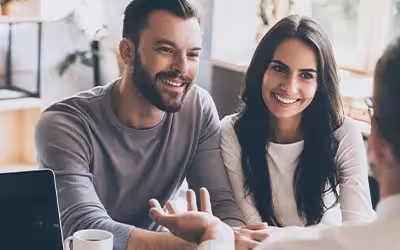 Happy couple getting advice about health insurance in the UK from an experienced broker. 