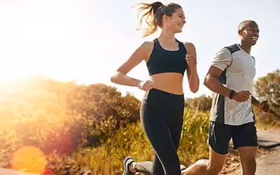 Healthy, happy couple running on the road in the countryside. 9 Tips When Comparing Health Insurance In The UK - 2025