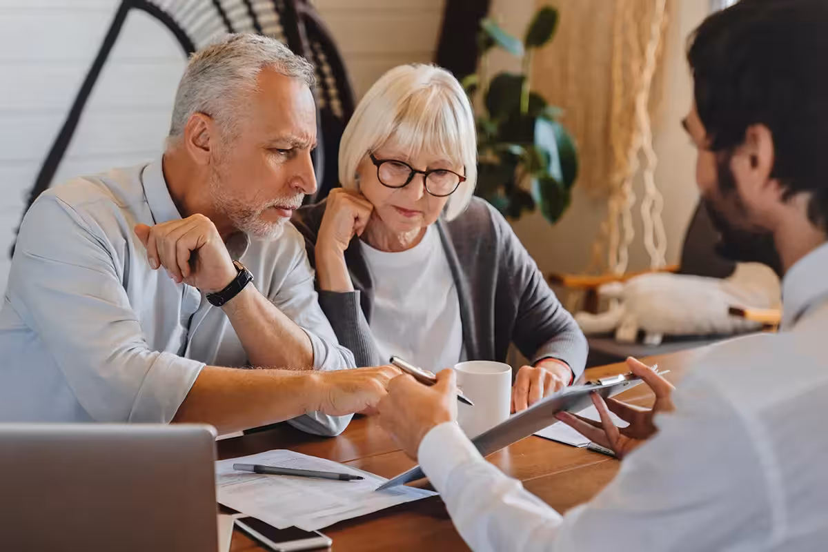 Financial advisor explaining paperwork to retired couple front of desk