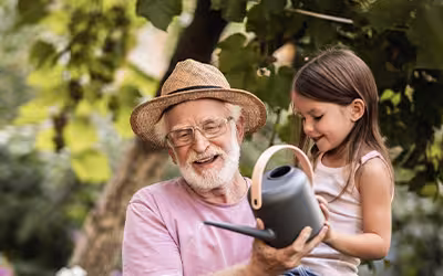 Little girl helping her grandpa watering plants 