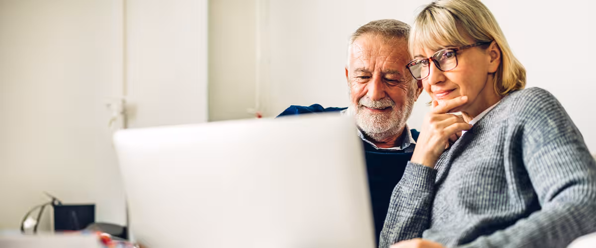 Senior couple reading about private medical insurance on their laptop