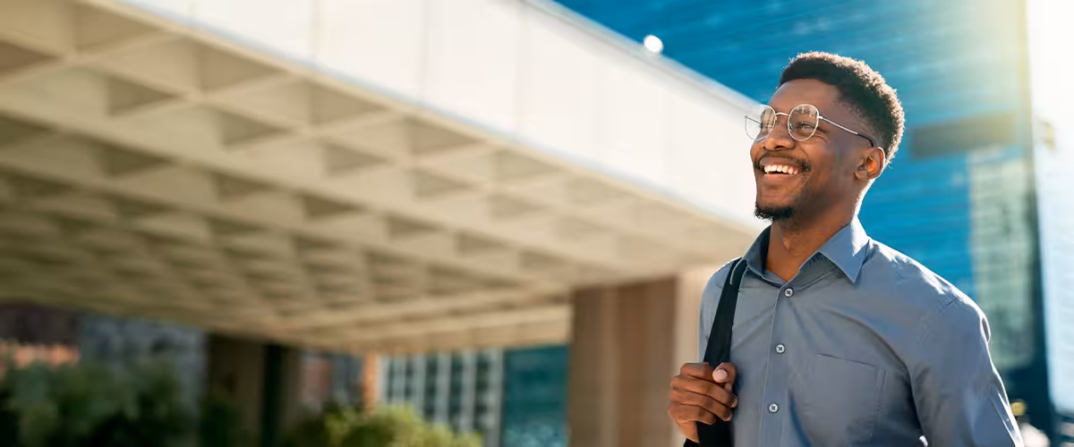A smiling professional walking outside an office building, representing a positive and cost-effective approach to managing company health insurance premiums