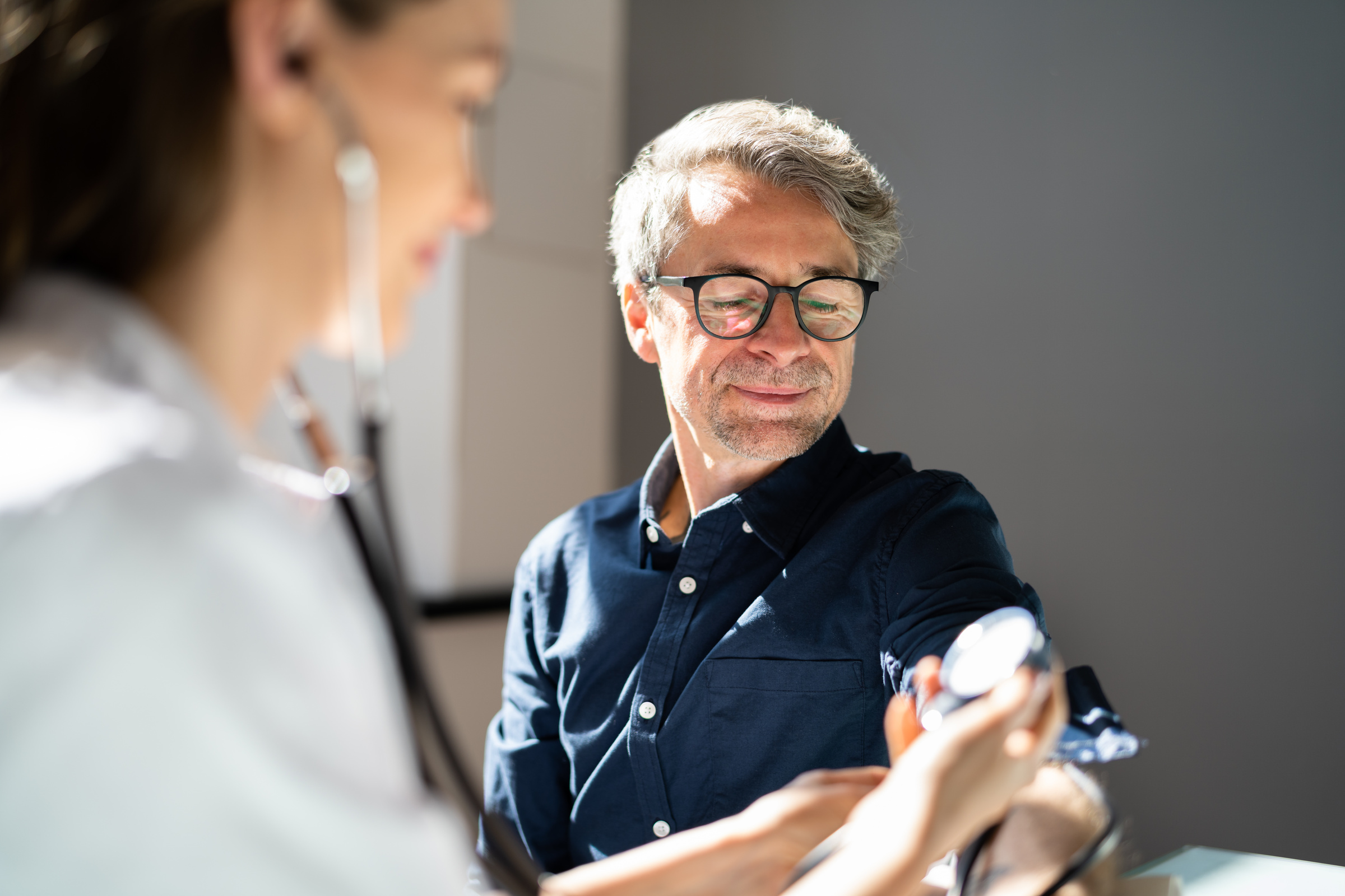 Doctor performing a routine health screening check on a patient at a UK clinic