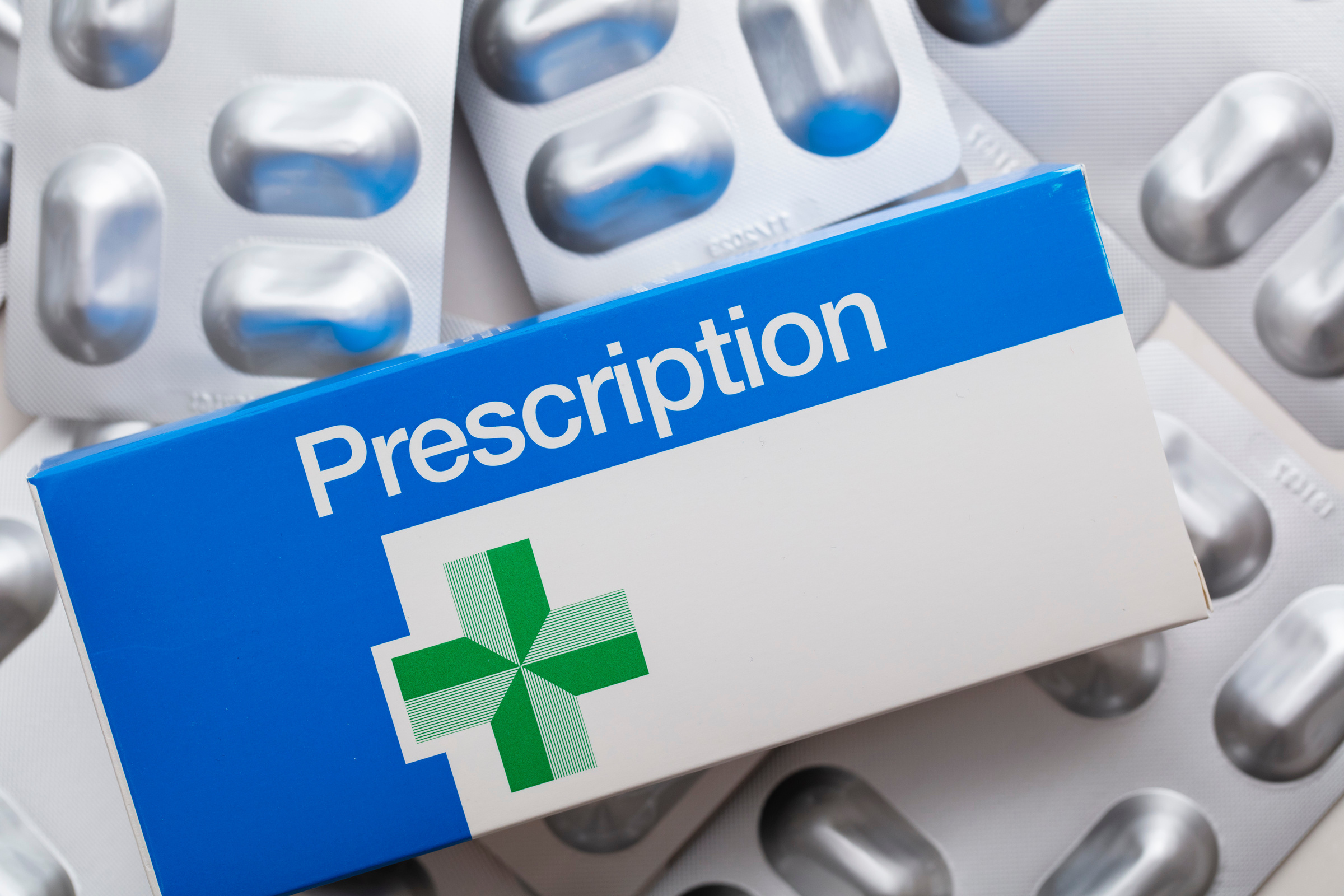 Pharmacist handing antibiotic medication to a customer at a UK NHS pharmacy counter