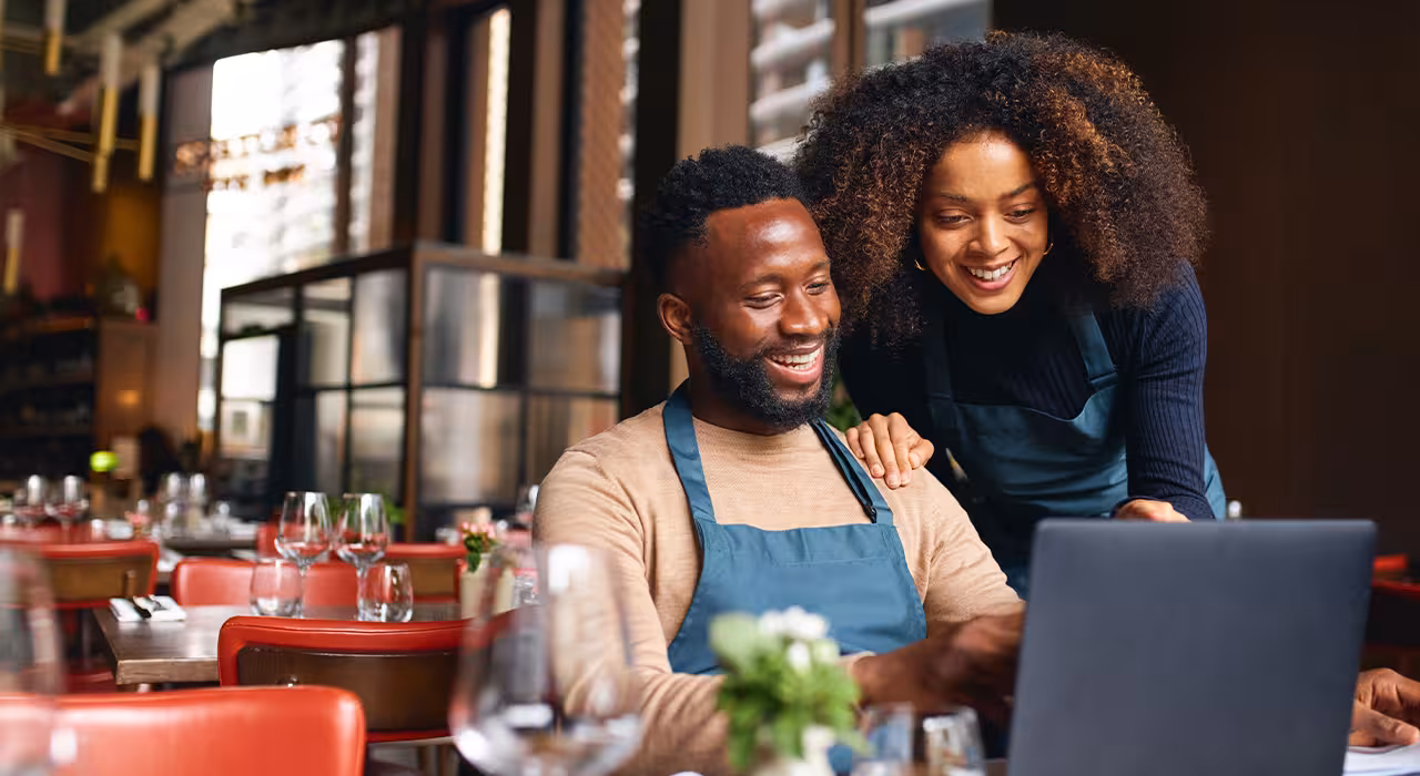 Small business owners using laptop in restaurant