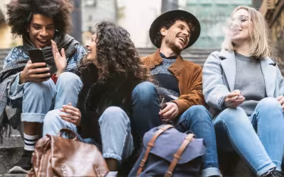 Young friends using phones, smoking and talking together outdoor