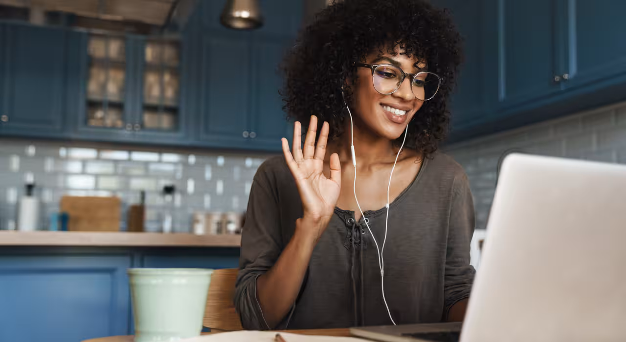 Young woman waving at screen on video call with Axa Health outpatient service