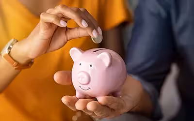 women putting money into a pink piggy bank