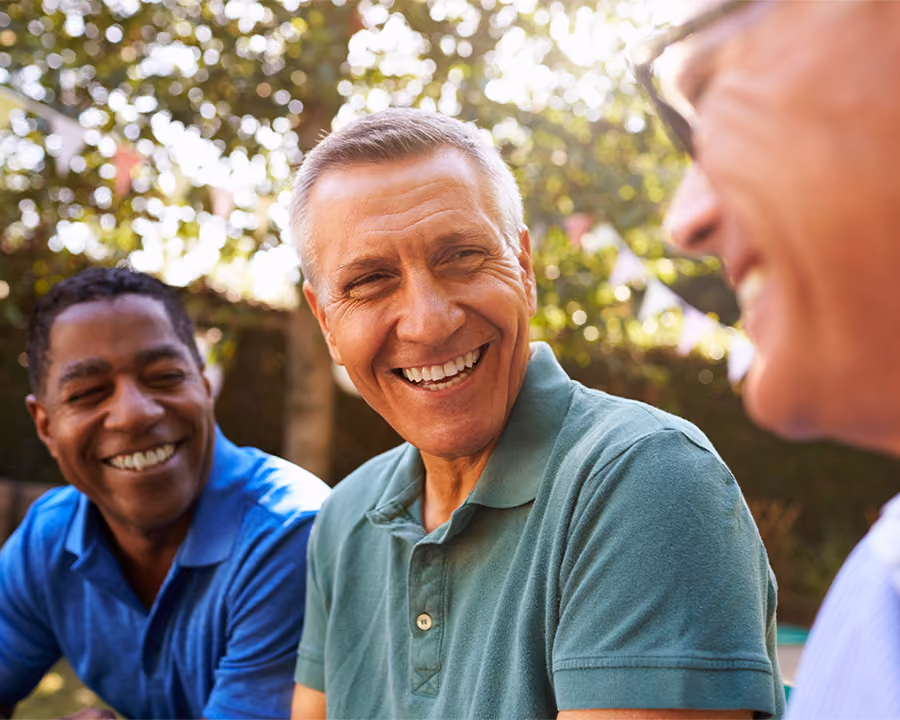 Three older friends laughing together outdoors