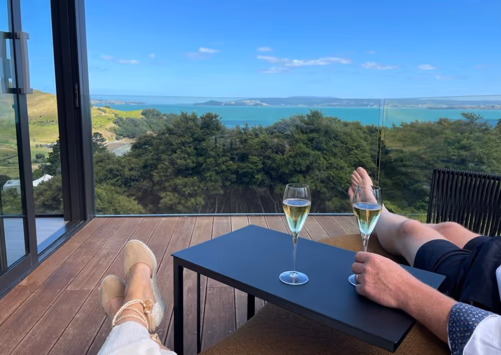 A couple sits on the balcony, drinking wine while watch the sea