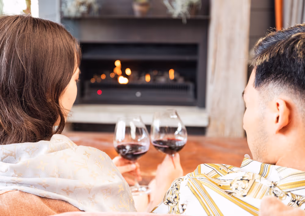 A couple drinks red wine by the fire on Waiheke Island