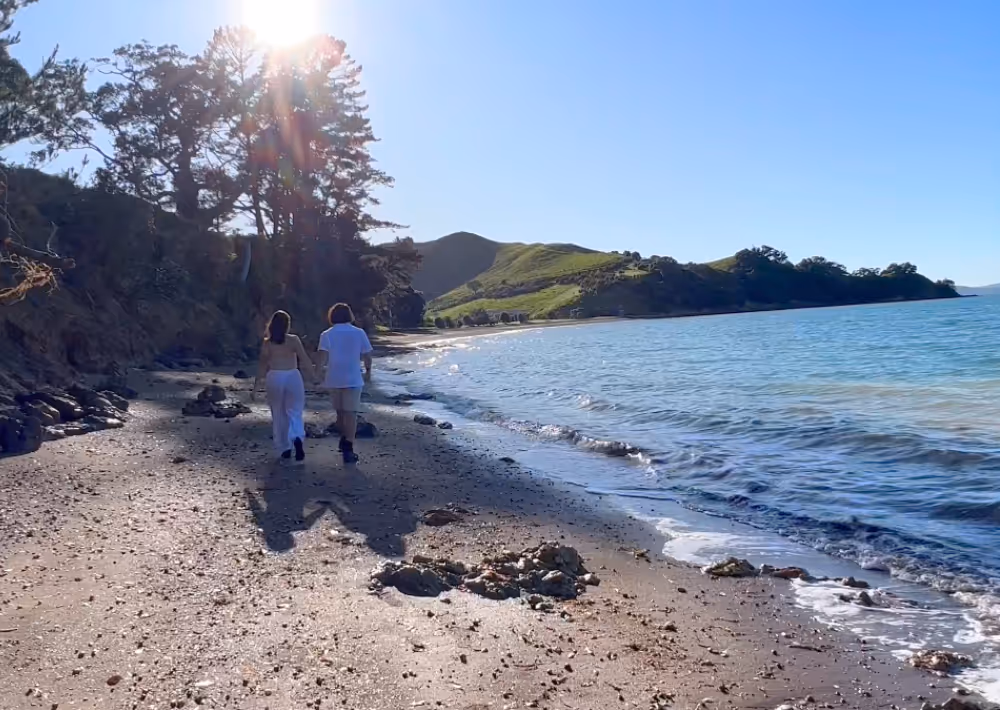 A couple walks on a private beach on Waiheke Island