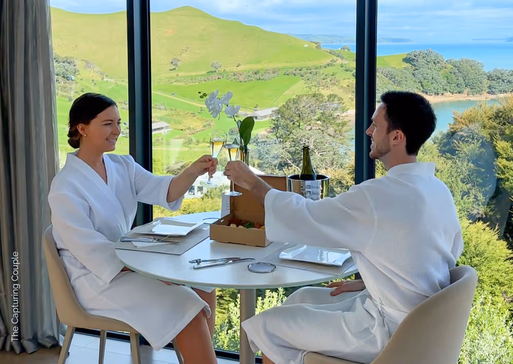 A couple toasts with an ocean view as their backdrop