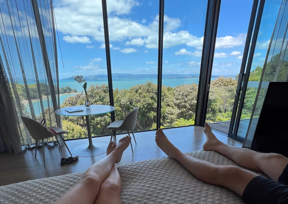 A couple rests on the bed and marvels at the ocean view