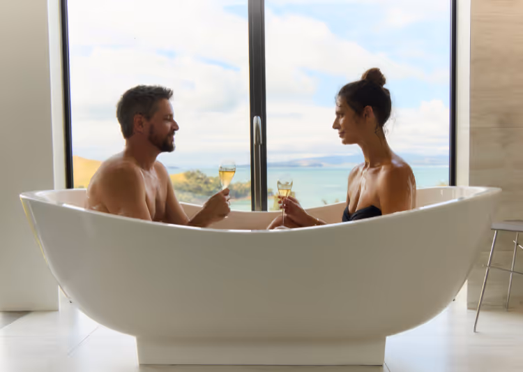A couple having a bath in Villa Joy's bathtub with an ocean view