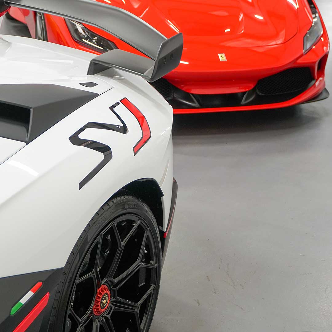 A view of the spoiler of one supercar and the front bumper of another behind it