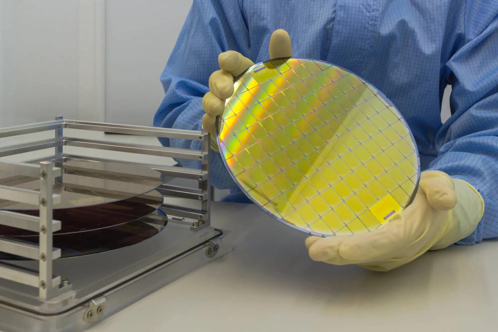 Person with white gloves holding a silicon wafer