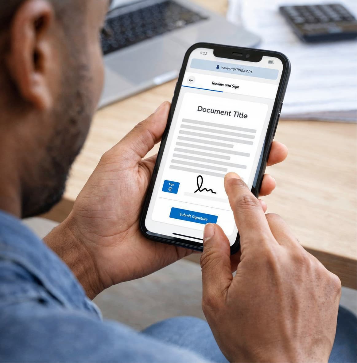 Man holding a smartphone displaying a digital document with the heading Document Title and a visible signature field as he taps the Submit Signature button. The screen shows a review and sign page with a typed signature and sign button, highlighting the ease of electronically signing documents from a mobile device in a modern office setting.