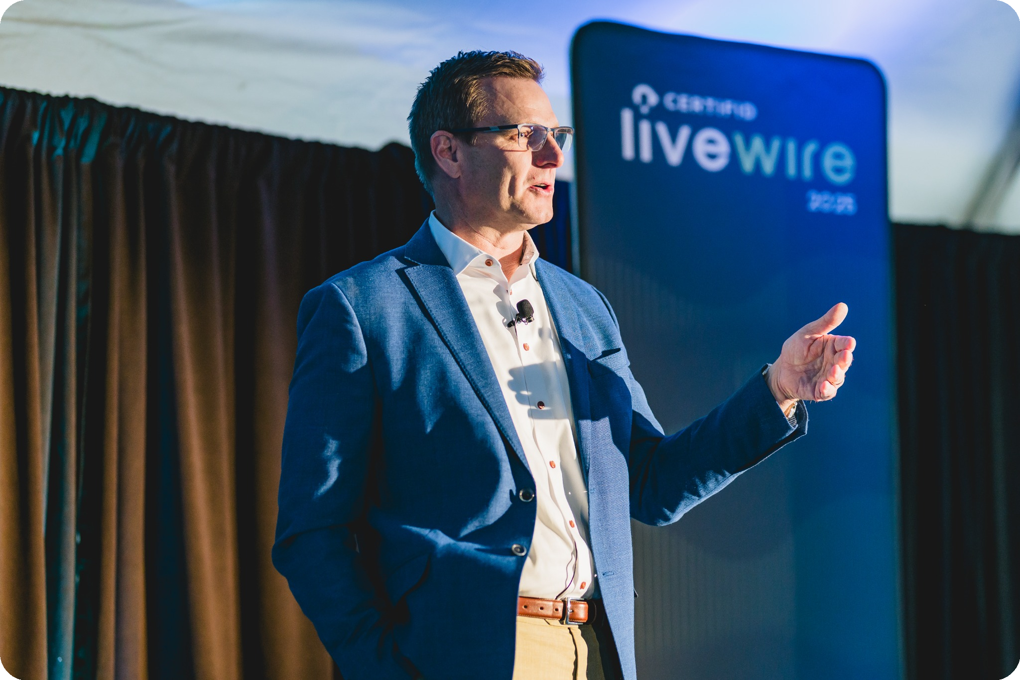 Tom Cronkright a blue blazer speaks on the main stage at LiveWire 2025.