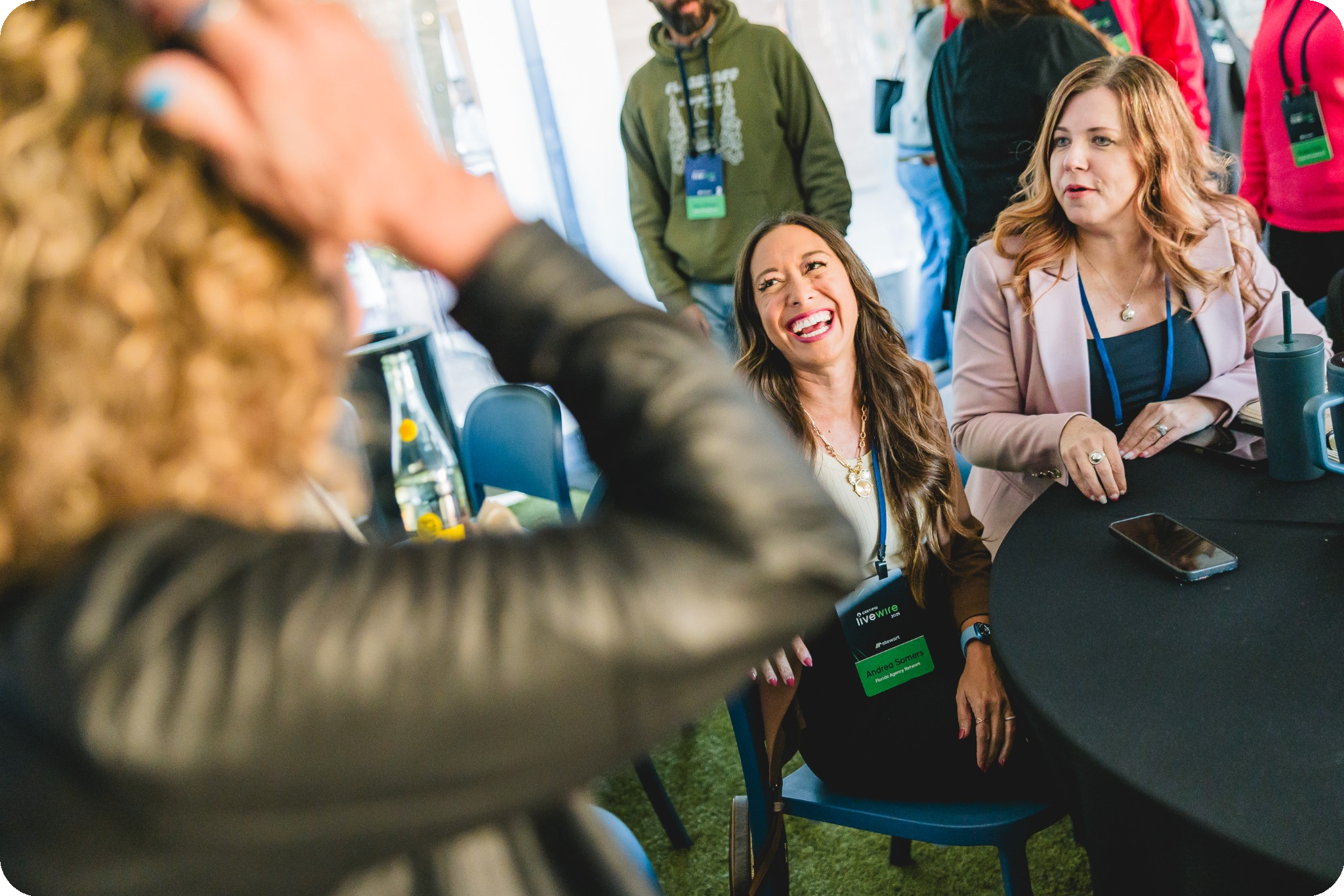 Three people are seated around a round table, laughing and engaging in conversation at LiveWire.