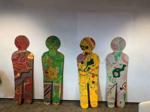 a picture of 4 wooden ply boards shapes as people with words and colours and prints painted and designed on to them to reflect the values of burnage bosy academy year 7 group