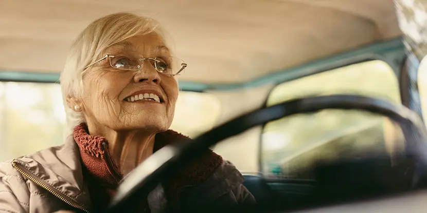 Older woman smiling while driving, representing recovery and restored vision after cataract surgery