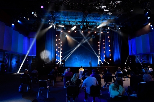 Stage set up in front of a live crowd with large stage lights
