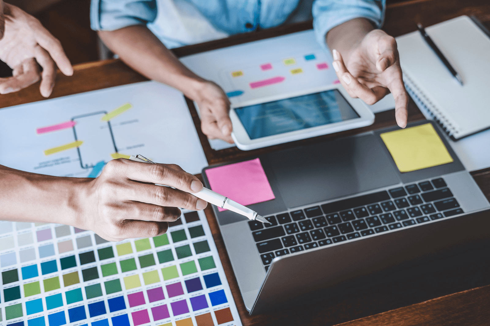 People looking at brand colors while pointing at a laptop