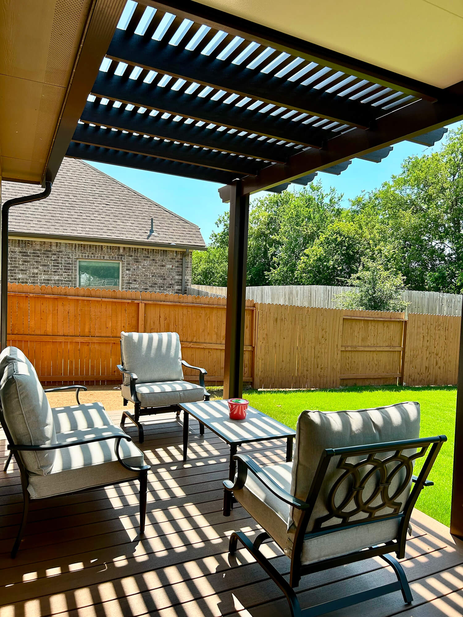 Pergola with chairs and table on patio.