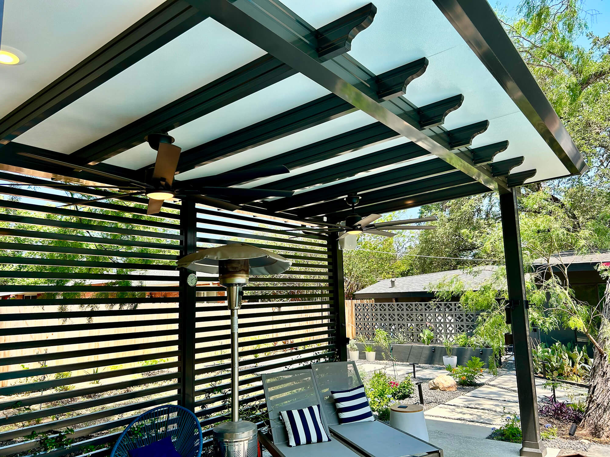 Modern patio cover with ceiling fans and heater in outdoor lounge area, San Antonio.