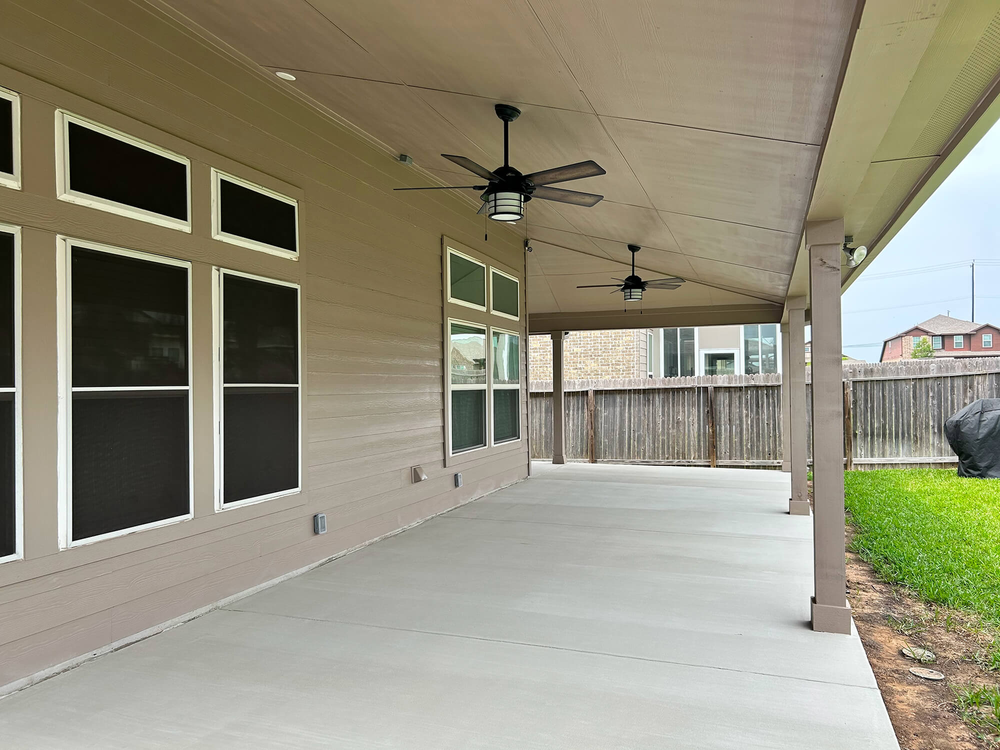Covered patio with fans in fenced backyard