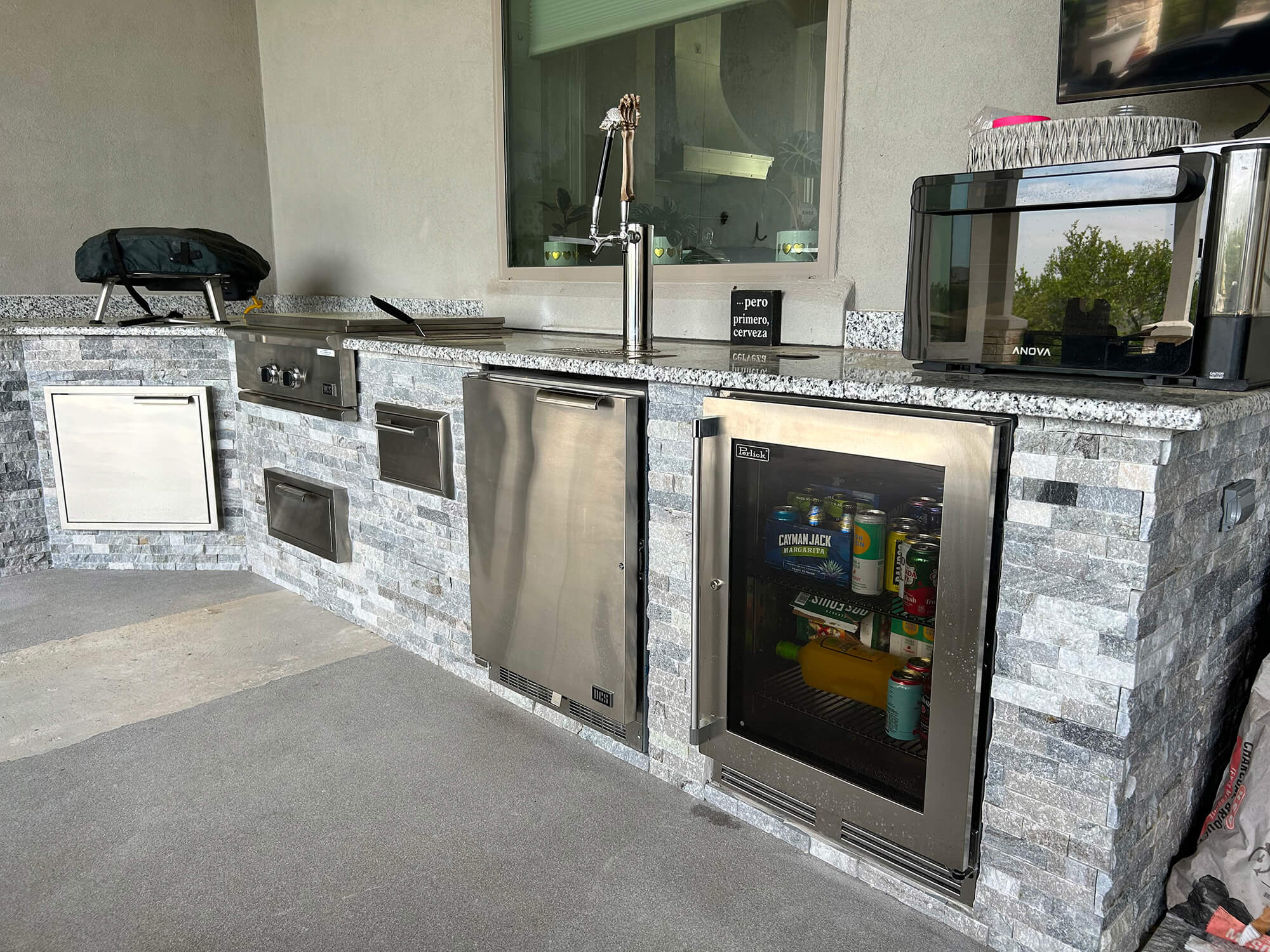 Outdoor kitchen with fridge, grill, and sink.