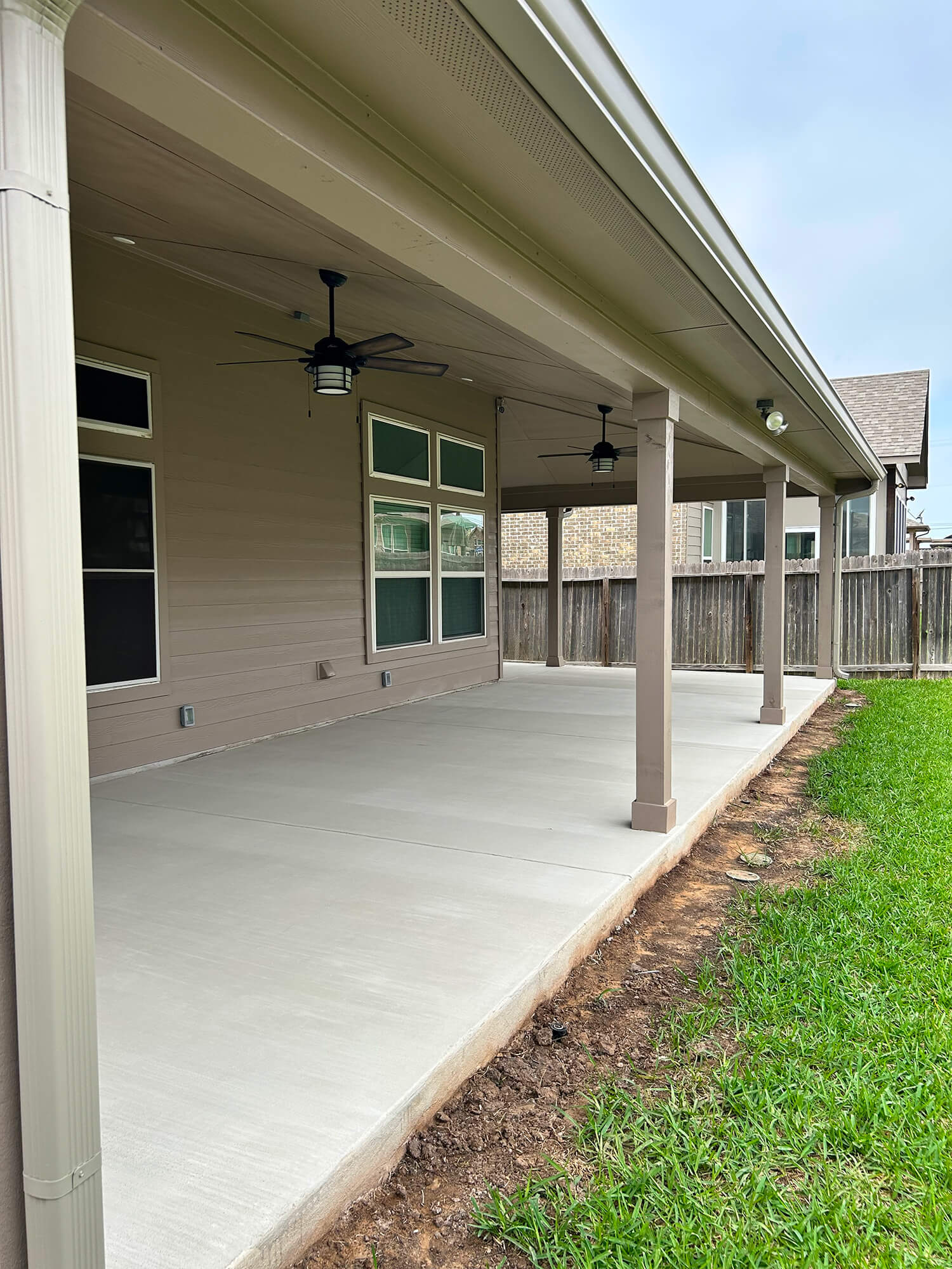 Newly installed patio cover with ceiling fans in San Antonio backyard.