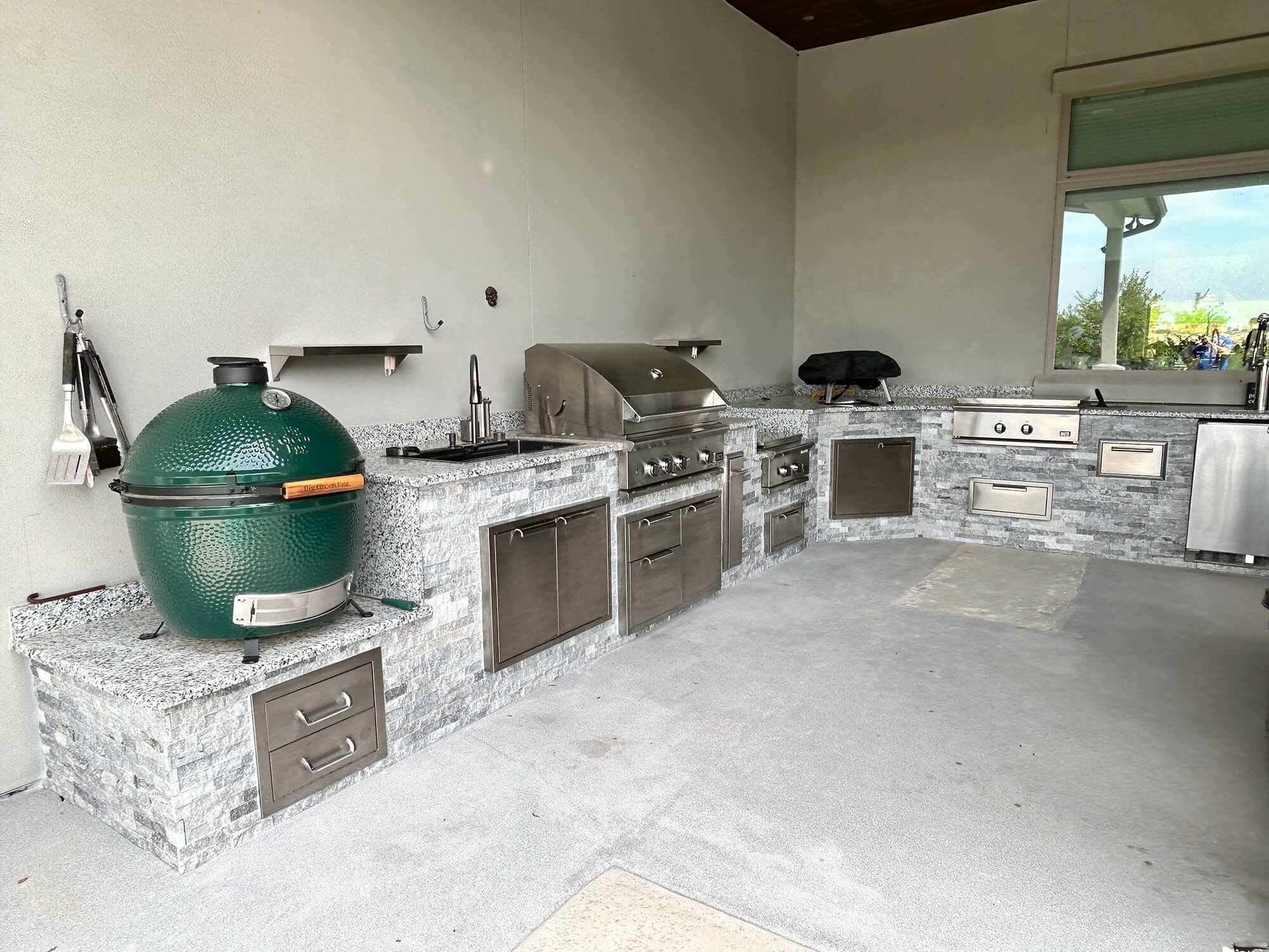Outdoor kitchen with grill and green ceramic smoker.