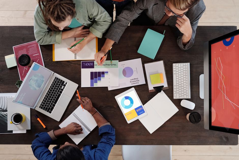 Three people analyzing charts and graphs at desk