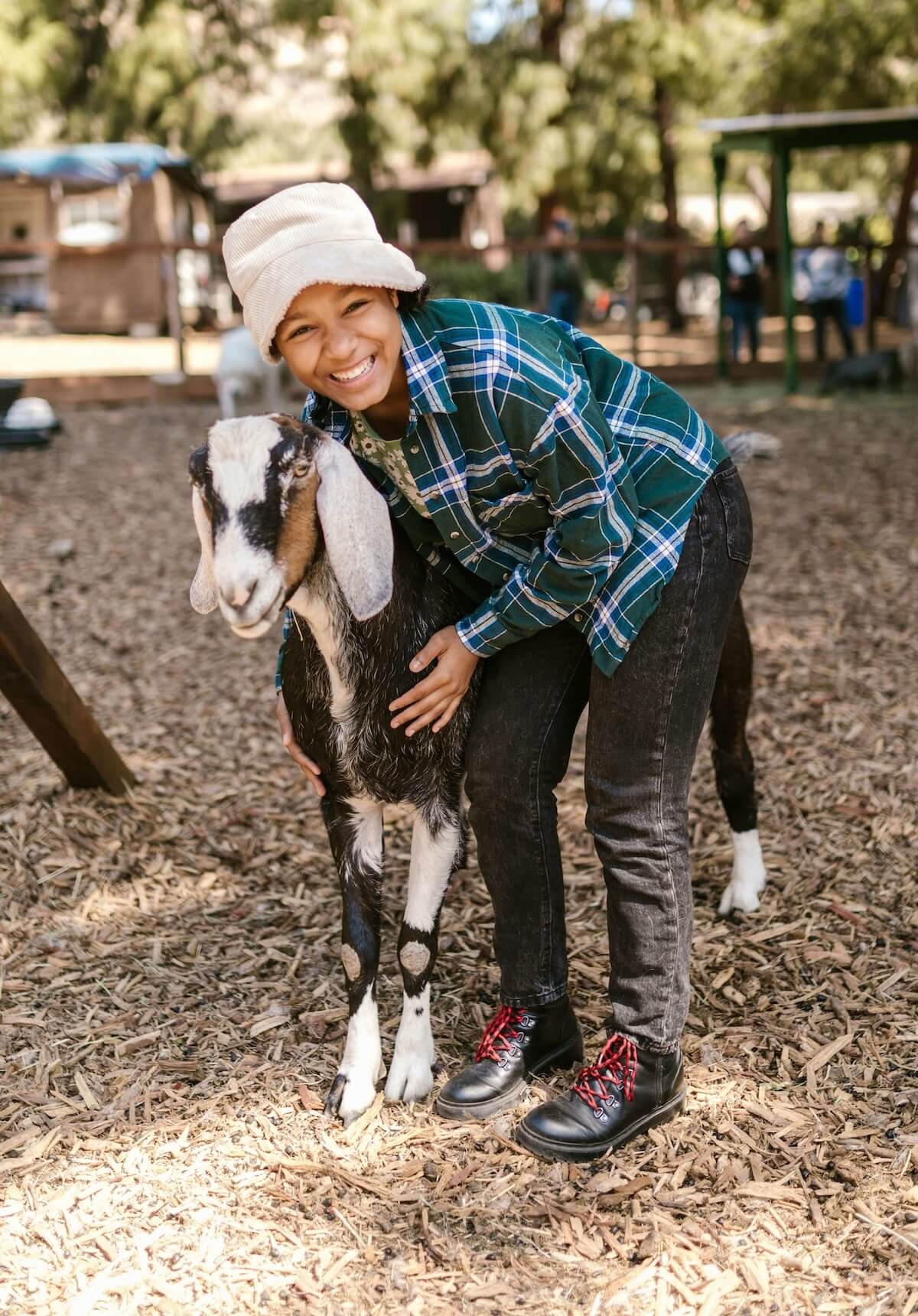 Young person smiling while hugging a goat in a farm setting, showcasing hands-on animal care, relevant to 4-H livestock projects and FarmKeep's support for youth agricultural development.